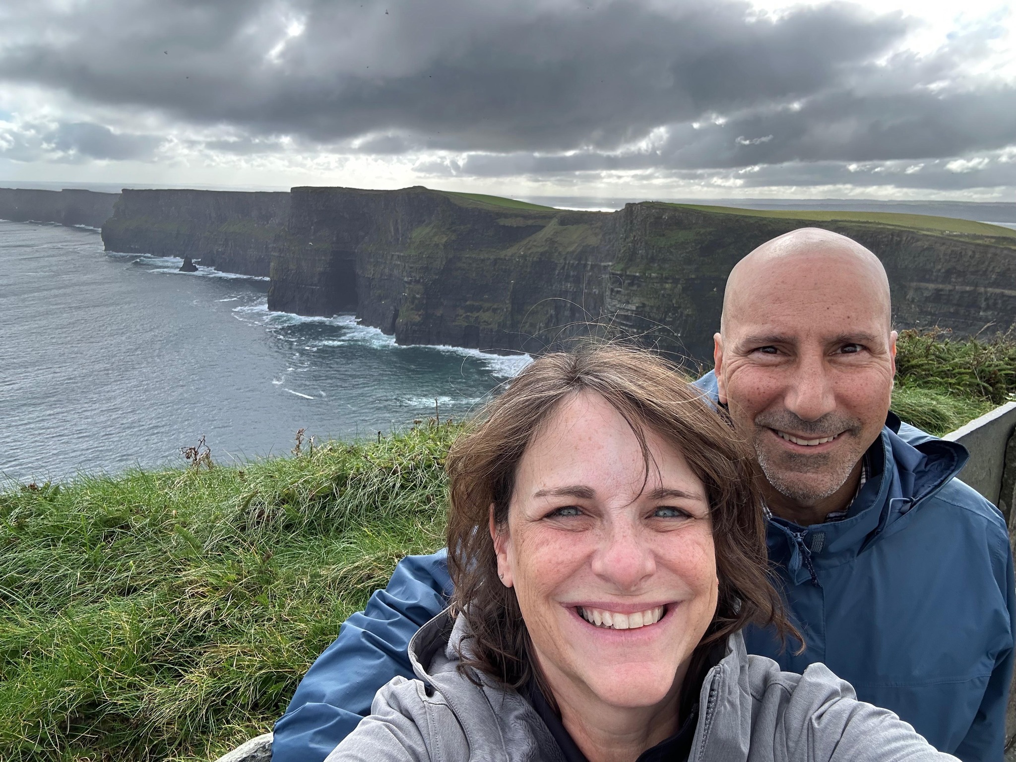 A happy couple taking a selfie in front of the Cliffs of Moher in Ireland